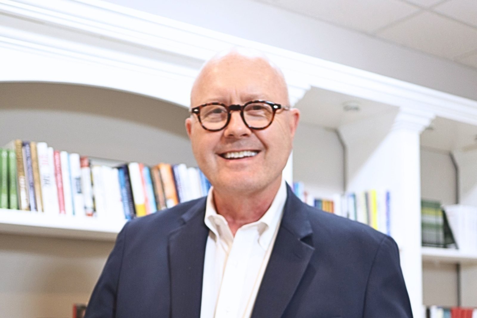 Richard Causey smiling in front of bookshelves