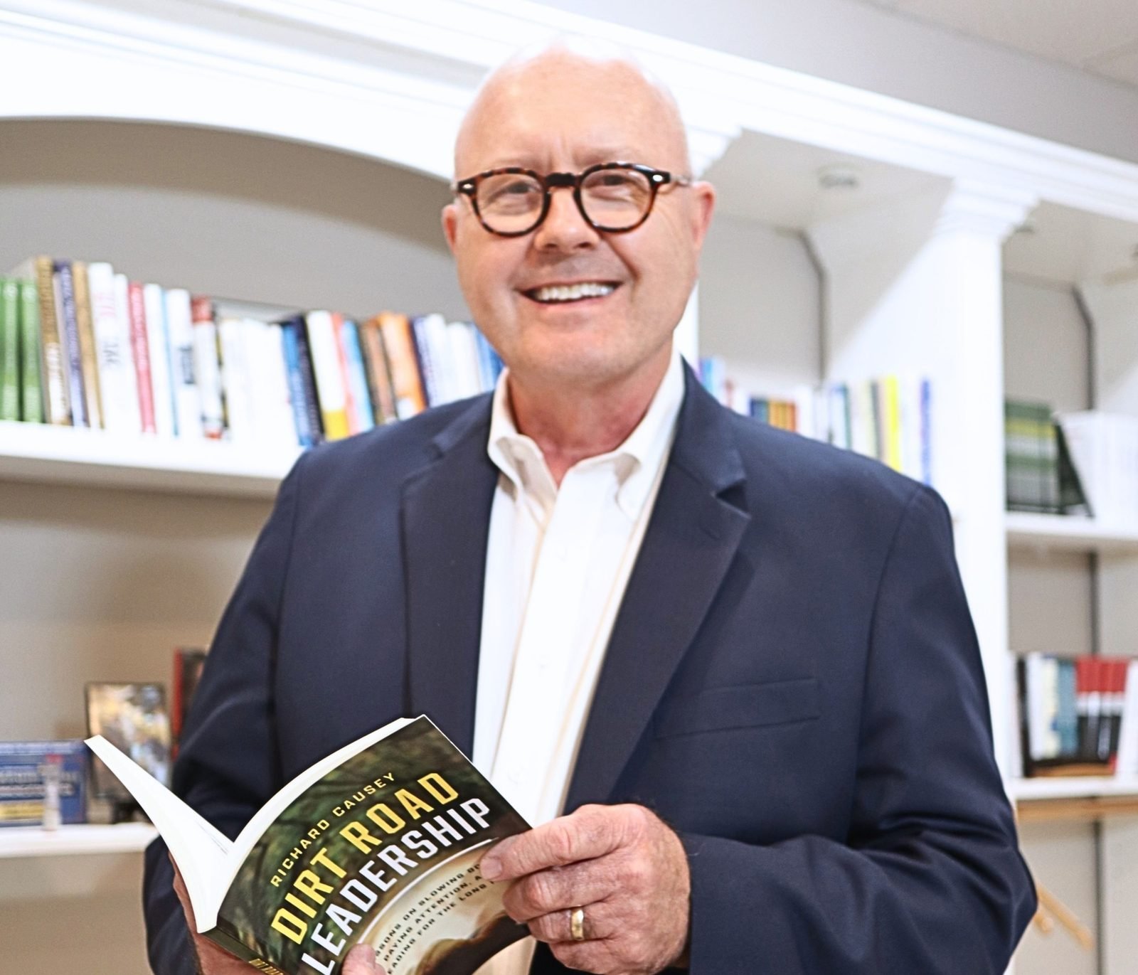 Richard Causey smiling and holding a copy of Dirt Road Leadership