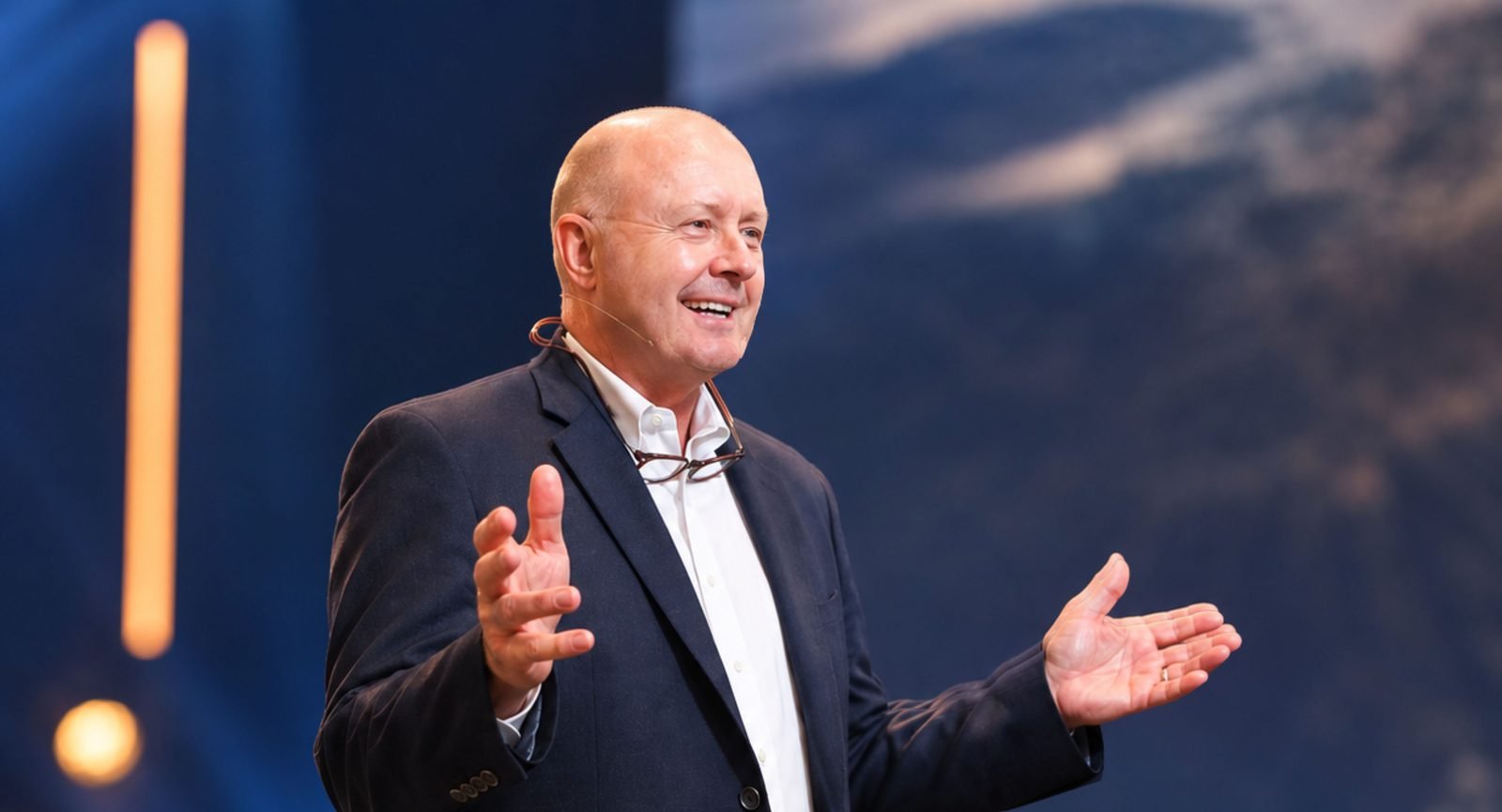 Richard Causey speaking on stage, smiling with open hands